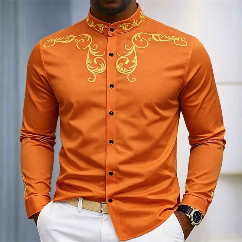 Man wearing an orange mandarin-collar shirt with gold scroll embroidery on shoulders and chest, paired with white pants.